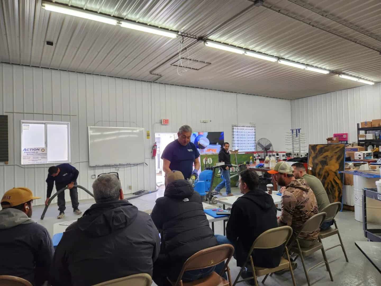 Instructor demonstrating epoxy floor coating tools and equipment during professional installer training