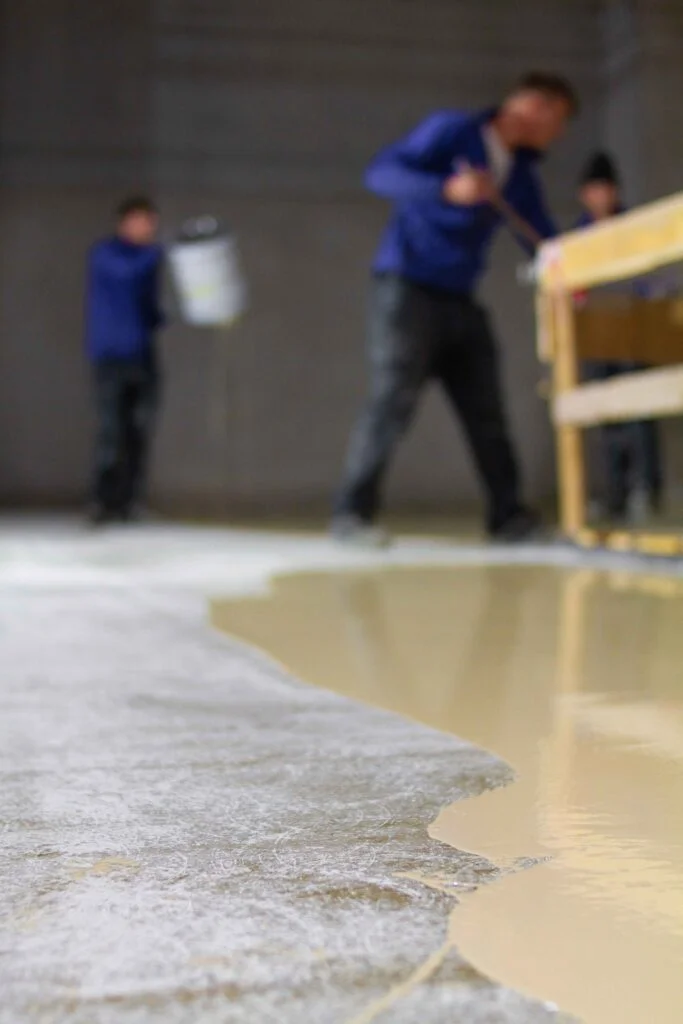 Epoxy base coat being applied to a prepared concrete floor during installation