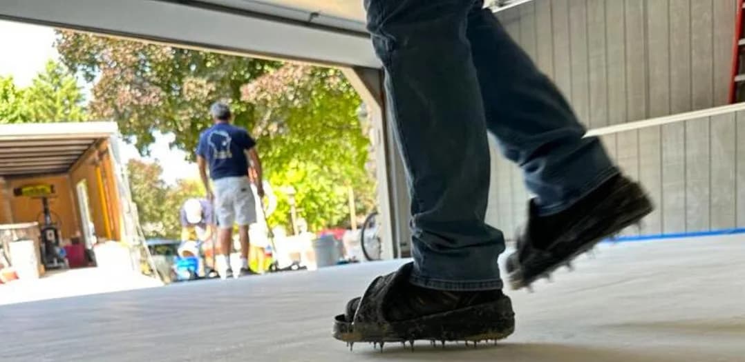 Installer walking on freshly applied epoxy floor coating during a professional installation, demonstrating durability and proper application technique in a commercial garage setting