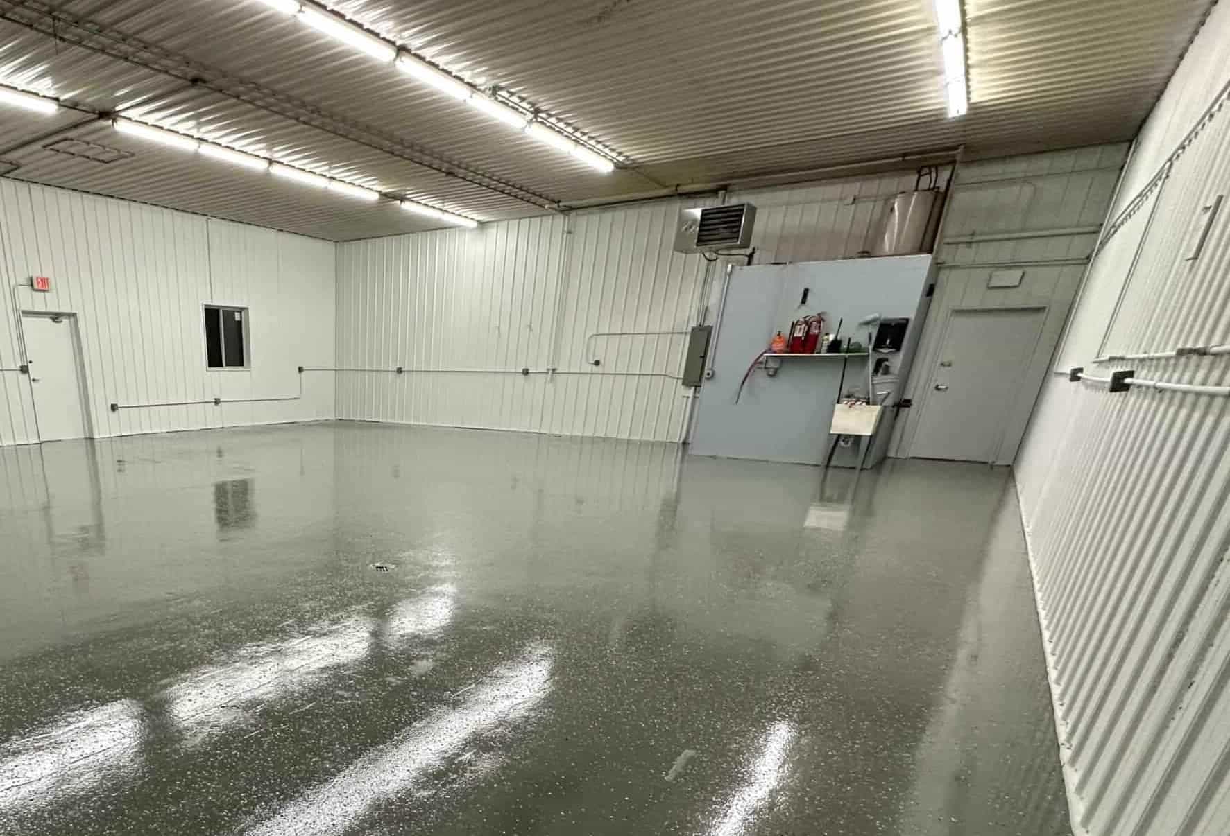 Glossy industrial epoxy floor coating in a commercial shop interior, reflecting overhead lights with a smooth, durable finish